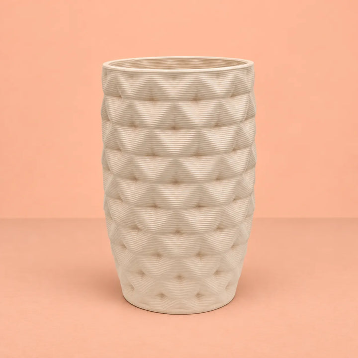 Vaso in argilla Rua alto Made in Italy, colore avorio con superficie lavorata a rilievo e forma leggermente affusolata, fotografato su sfondo pesca.