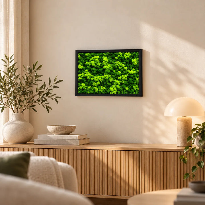 Quadro verde di licheni stabilizzati 45x33 cm con cornice nera sopra una madia in legno in soggiorno luminoso
