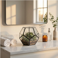 Terrarium Zoe esagonale piante grasse su comodino bagno marmo bianco. Asciugamani candela sapone. Atmosfera spa rilassante golden hour moderna.